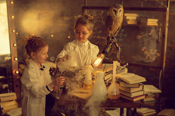 schoolgirls in white coats with owl making experiment in lab