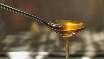 Delicious honey pours out of the spoon close up
