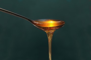 Delicious honey pours out of the spoon close up