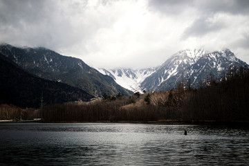 Landscape view low light tone with snow covered mountains and forest in late winter at Kamikochi, Japan National Park, Nagano