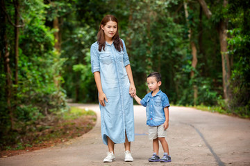 Happy mother and adorable little boy enjoying warm weather at beautiful park