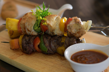 Fish and beef barbecue with tomato and bell pepper on wooden skewers