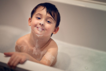 boy taking bubble bath and looking at the camera