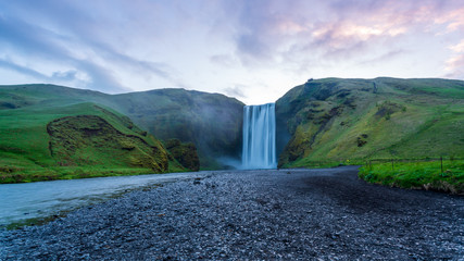 Fototapeta na wymiar road in mountains and SKÓGAFOSS waterfalls sunrise in Iceland 