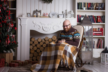 an old man in a plaid rug sits in a rocking chair