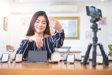 Happy girl blogger at cafe talking about makeup and beauty and recording video tutorial for...