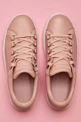 Stylish pink female shoes on pastel background, copy space. New sneakers on pink background. Beauty and fashion concept. Flat lay, top view. Overhead shot