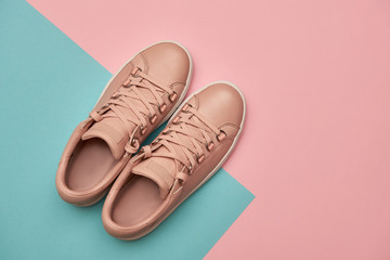 Stylish pink female shoes on pastel background, copy space. New sneakers on pink and blue background. Beauty and fashion concept. Flat lay, top view. Overhead shot