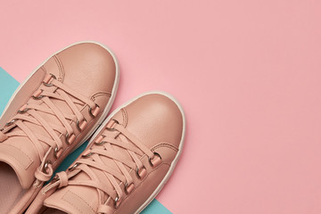 Stylish pink female shoes on pastel background, copy space. New sneakers on pink and blue background. Beauty and fashion concept. Flat lay, top view. Overhead shot