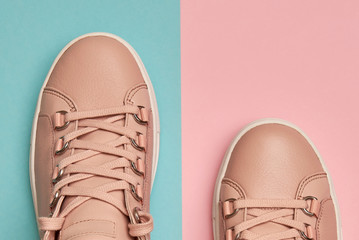 Stylish pink female shoes on pastel background, copy space. New sneakers on pink and blue background. Beauty and fashion concept. Flat lay, top view. Overhead shot