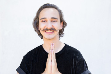 Smiling young man with mustache praying. Closeup shot of cheerful believer posing. Religion concept