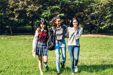 Group of smiling international students or teenagers standing with book in park at university.Education and friendship Concept