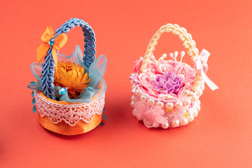 a pair of handmade baskets of ribbons and flowers on a pink background
