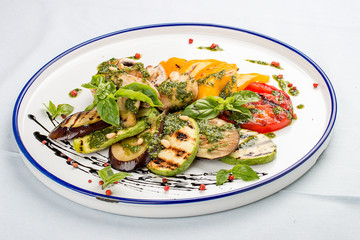 Grilled vegetables - tomatoes, zucchini, eggplant, sweet pepper, mushrooms. In a white plate