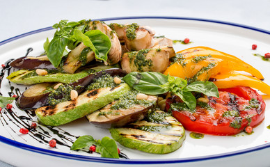 Grilled vegetables - tomatoes, zucchini, eggplant, sweet pepper, mushrooms. In a white plate