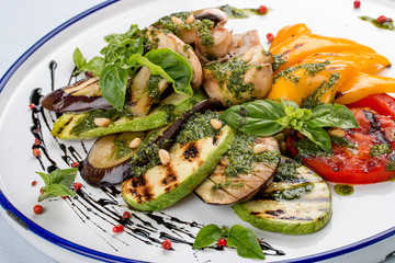 Grilled vegetables - tomatoes, zucchini, eggplant, sweet pepper, mushrooms. In a white plate