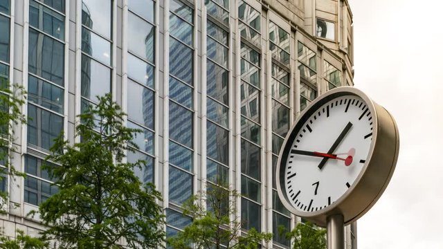 Time lapse of a large clock in a modern city with office buildings in the back ground, Canary Wharf, London