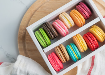 Colourful macaroons in white box top view background