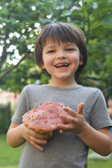 Fresh porcini mushroom in child hand. Happy boy hold big cep mushroom