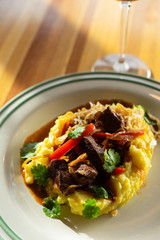 Close up of a traditional russian beef stroganoff with gravy, mashed potatoes and caramelized onion served on a summer terrace