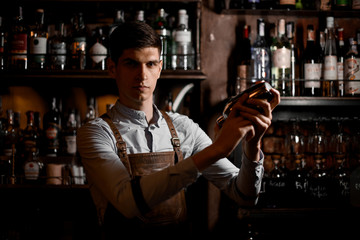 Professional male bartender holding in hands a steel shaker