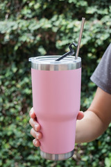 Hand on thermos tumbler mug with metal drinking straw