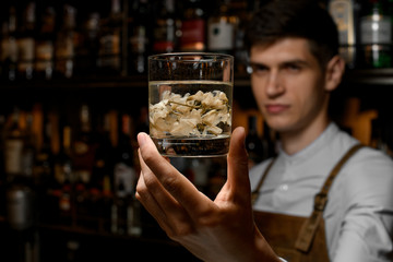 Bartender serving a transparent alcoholic cocktail in the glass with dry flowers