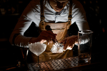 Professional bartender in leather apron making a crushed with a special fork