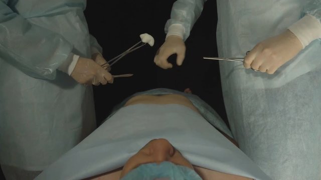 Two surgeons with medical instruments are advised before the operation, the patient is on the table under anesthesia