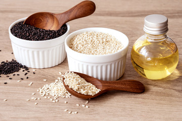 organic Black and a white sesame seeds in wooden spoon with oil bottle