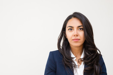 Serious young businesswoman. Portrait of beautiful young brunette businesswoman looking at camera isolated on grey background. Emotion concept