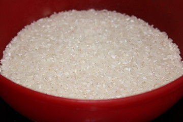 white raw rice poured into a red bowl
