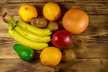 Assortment of tropical fruits on wooden table. Still life with bananas, mango, oranges, avocado, grapefruit and kiwi fruits