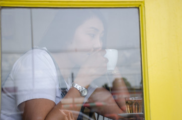 .Asian girls are enjoying coffee in a coffee shop that looks through the glass.