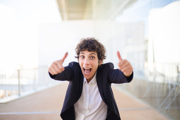 Emotional businesswoman showing thumbs up. Excited businesswoman in formal wear showing thumbs up...