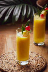 Tropical  cocktail pineapple  in a glasses, garnished with  cherries maraschino on wooden  table .