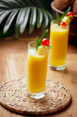 Tropical  cocktail pineapple  in a glasses, garnished with  cherries maraschino on wooden  table .