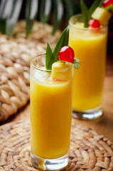 Tropical  cocktail pineapple  in a glasses, garnished with  cherries maraschino on wooden  table .