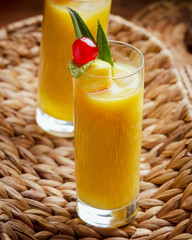 Tropical  cocktail pineapple  in a glasses, garnished with  cherries maraschino on wooden  table .