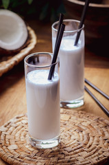 Coconut milk  in glasses with nuts on wooden board.