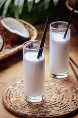 Coconut milk  in glasses with nuts on wooden board.