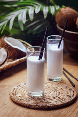 Coconut milk  in glasses with nuts on wooden board.