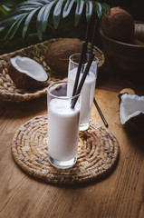 Coconut milk  in glasses with nuts on wooden board.
