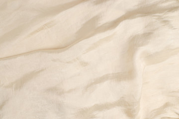 Fototapeta na wymiar Soft smooth beige silk fabric background. Fabric texture.