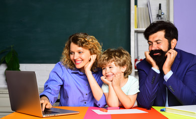 September 1. Child from elementary school with parents in school. Beginning of lessons. Ready to study. Cute pupil and his father and mother in classroom. Happy schoolboy at lesson. School education.