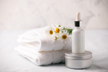 Fototapeta na wymiar Organic vegan natural cosmetics concept. Chamomile flowers and cosmetic bottles of cream and serum essential on white background. Zero waste cosmetic package
