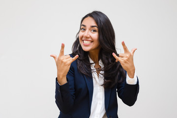Happy businesswoman gesturing with hands. Excited young woman showing rock n roll symbol and...