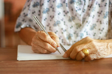 Asian elderly woman Holding a pen to write greetings to granddaughter. On the wedding day
