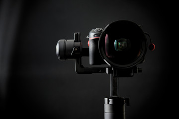 Close-up of gimbal stabilizer, and dsl camera with low-key lighting and a black background