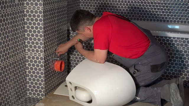 Plumber man prepare for hanging toilet bowl pan in new modern bathroom
